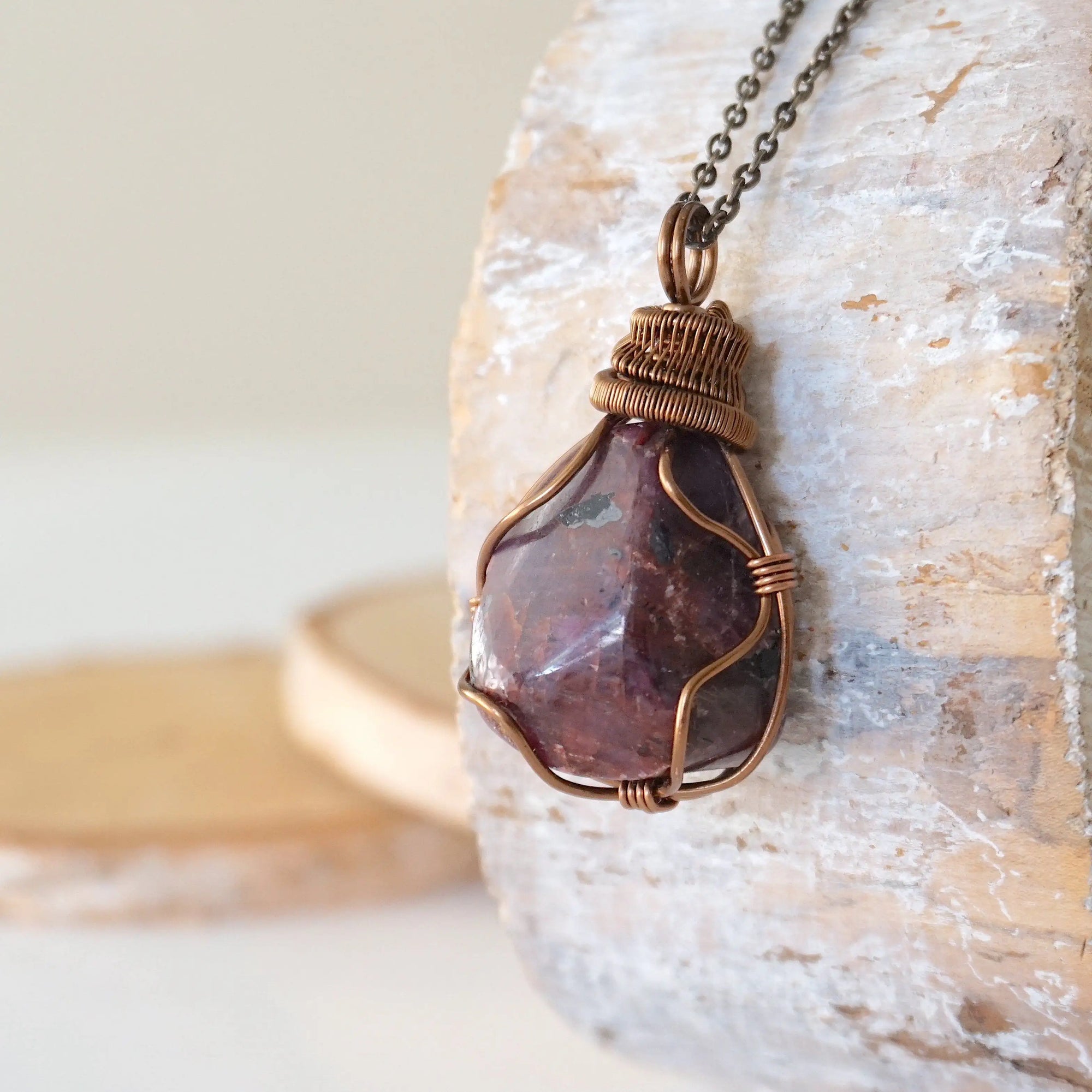 Left side view of large polished raw ruby pendant highlighting antique bronze wire wrap craftsmanship — men's statement crystal necklace, nickel-free copper wire
