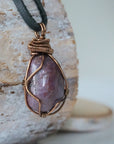 Right side view of men's large handcrafted polished raw ruby pendant showing bold antique bronze artisan wire wrapping detail