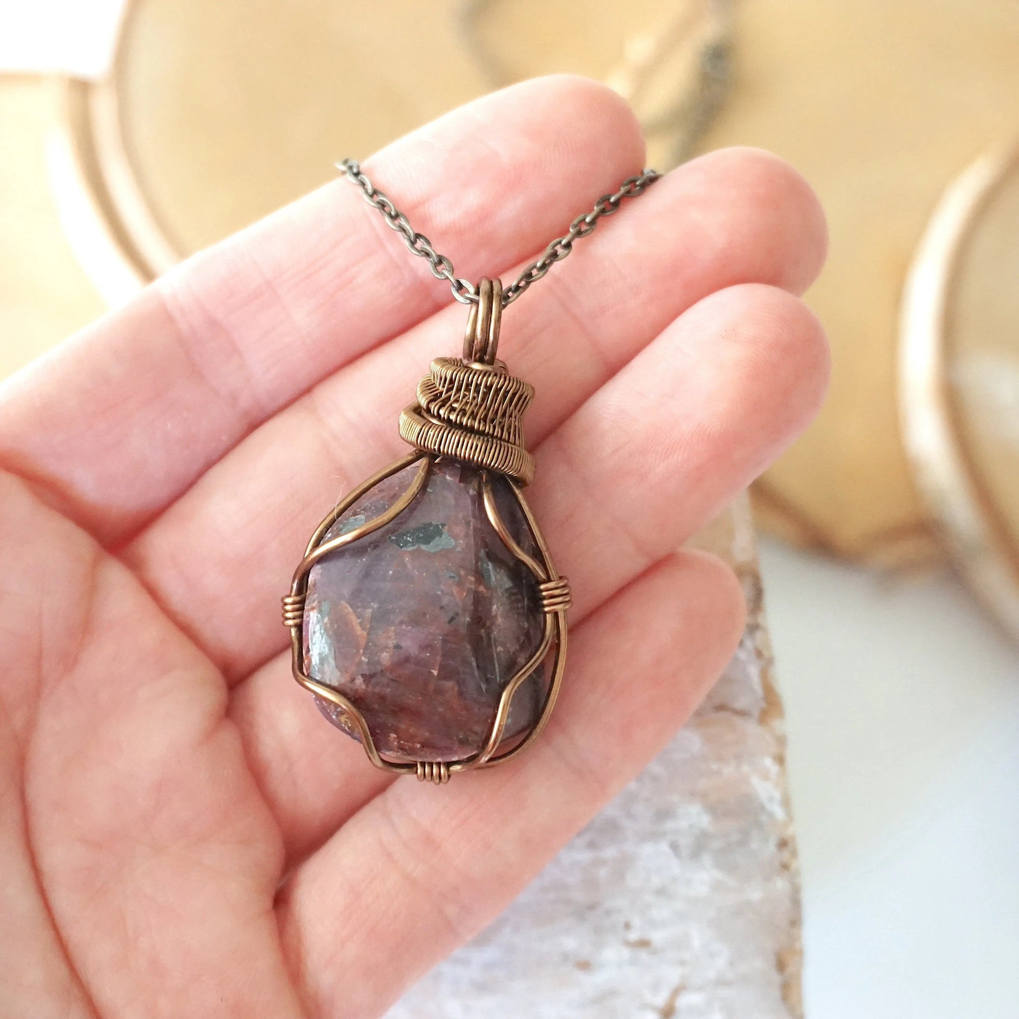 Large polished raw ruby pendant held in hand to show size — 100 to 120 carat natural ruby in antique bronze wire wrapping, men's statement crystal necklace