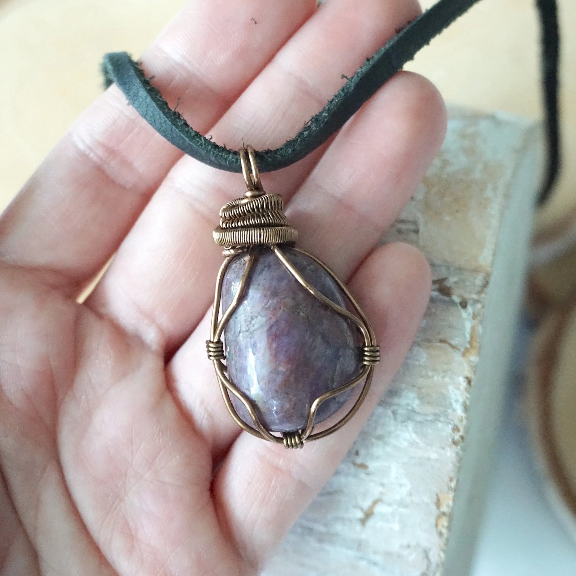 Large polished raw ruby pendant held in hand to show size — 100 to 120 carat natural ruby in antique bronze wire wrapping, men's statement crystal necklace