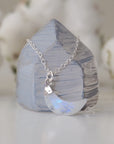 Side angle close-up of faceted rainbow moonstone crescent moon pendant in 925 sterling silver setting on sterling silver chain, June birthstone necklace.
