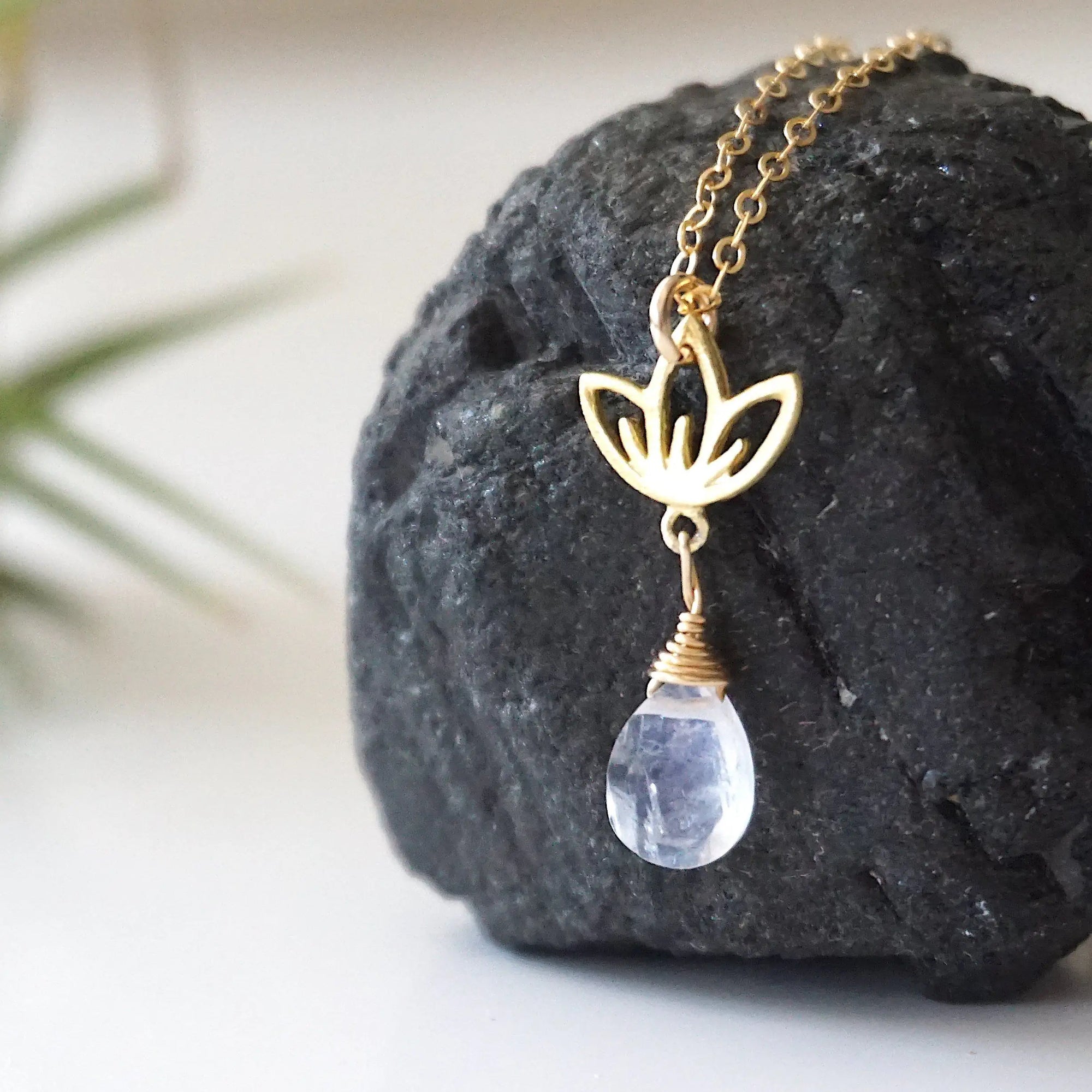 Left angle close-up highlighting handcrafted details of rainbow moonstone and lotus necklace, gold vermeil lotus charm and faceted pear moonstone pendant.