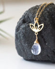Left angle close-up highlighting handcrafted details of rainbow moonstone and lotus necklace, gold vermeil lotus charm and faceted pear moonstone pendant.