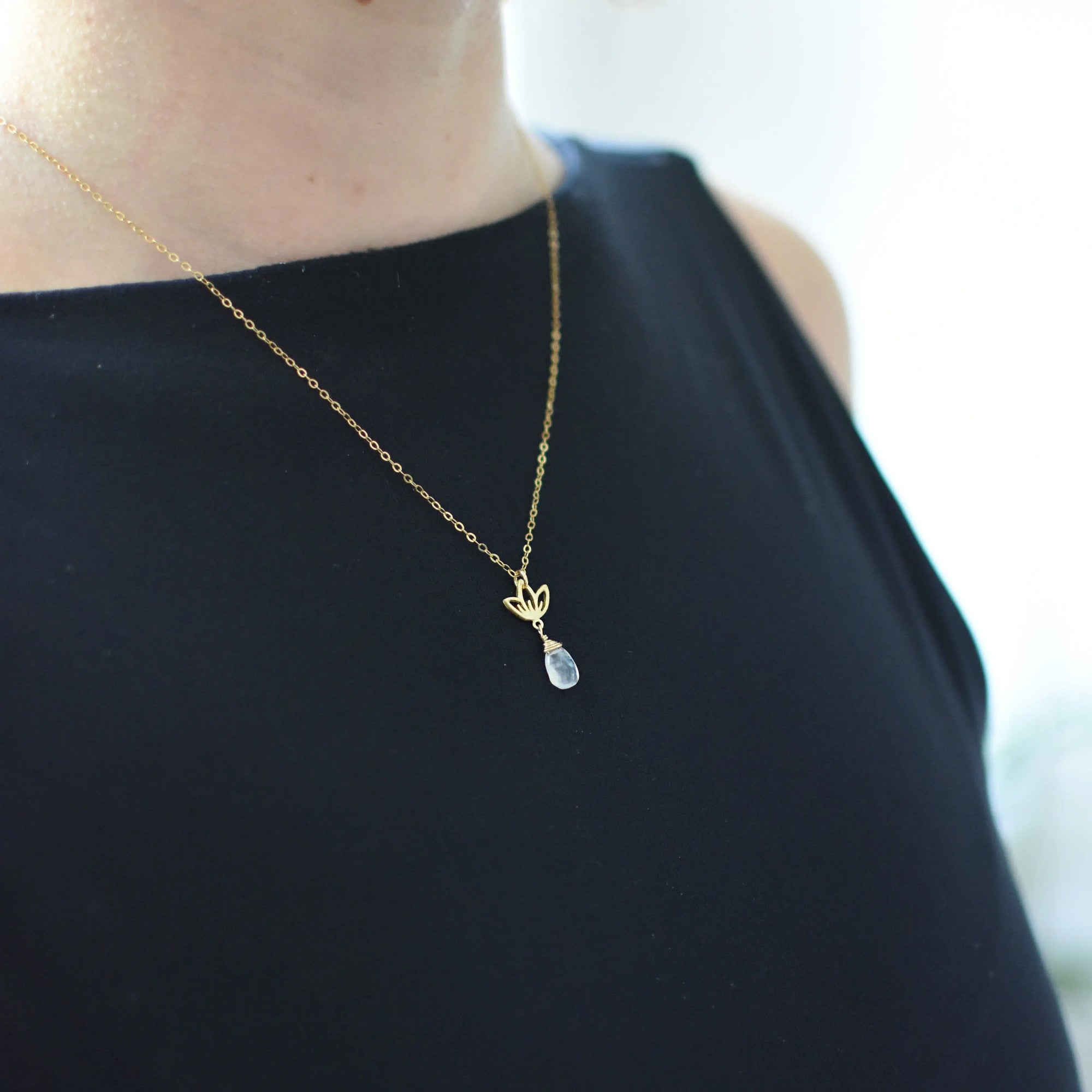 Rainbow moonstone and lotus necklace worn on a female model, faceted pear moonstone pendant with gold vermeil lotus charm on 14k gold filled chain.