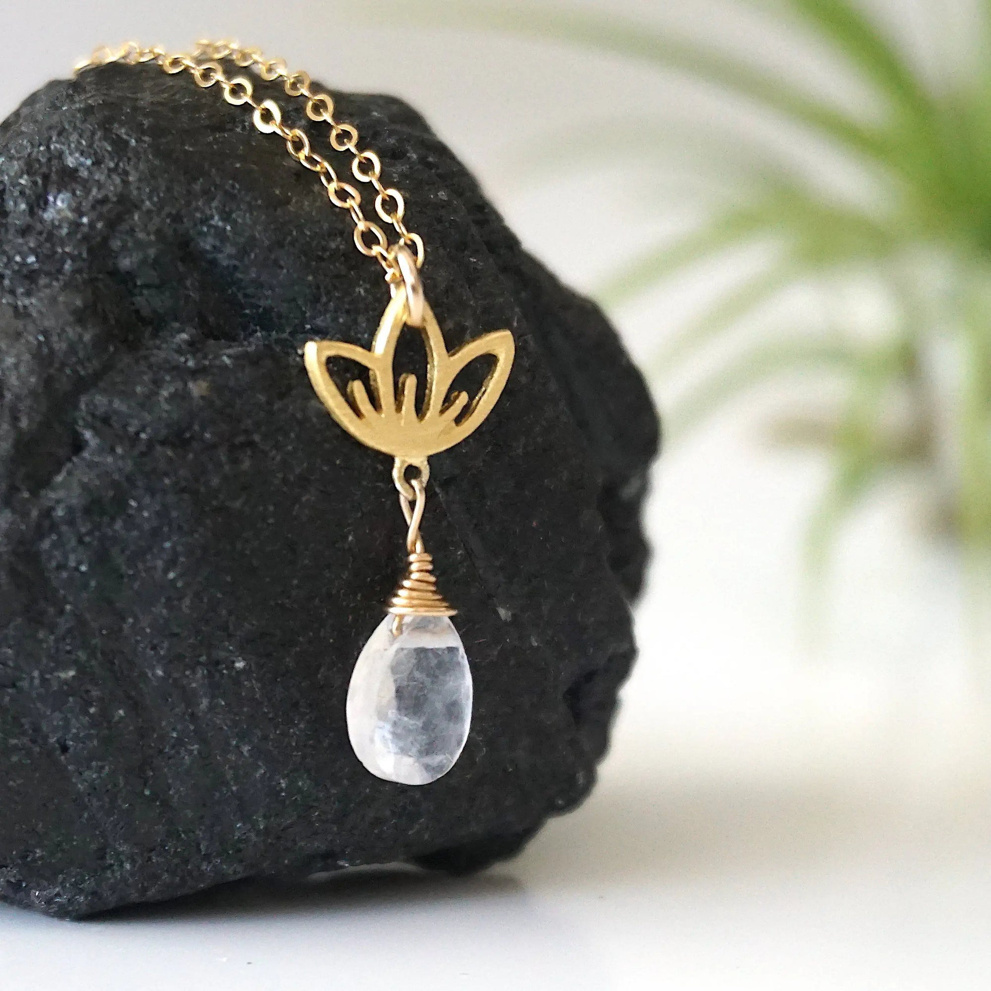 Right angle close-up showing artisan design of rainbow moonstone and lotus necklace, gold vermeil lotus charm with faceted pear rainbow moonstone drop.