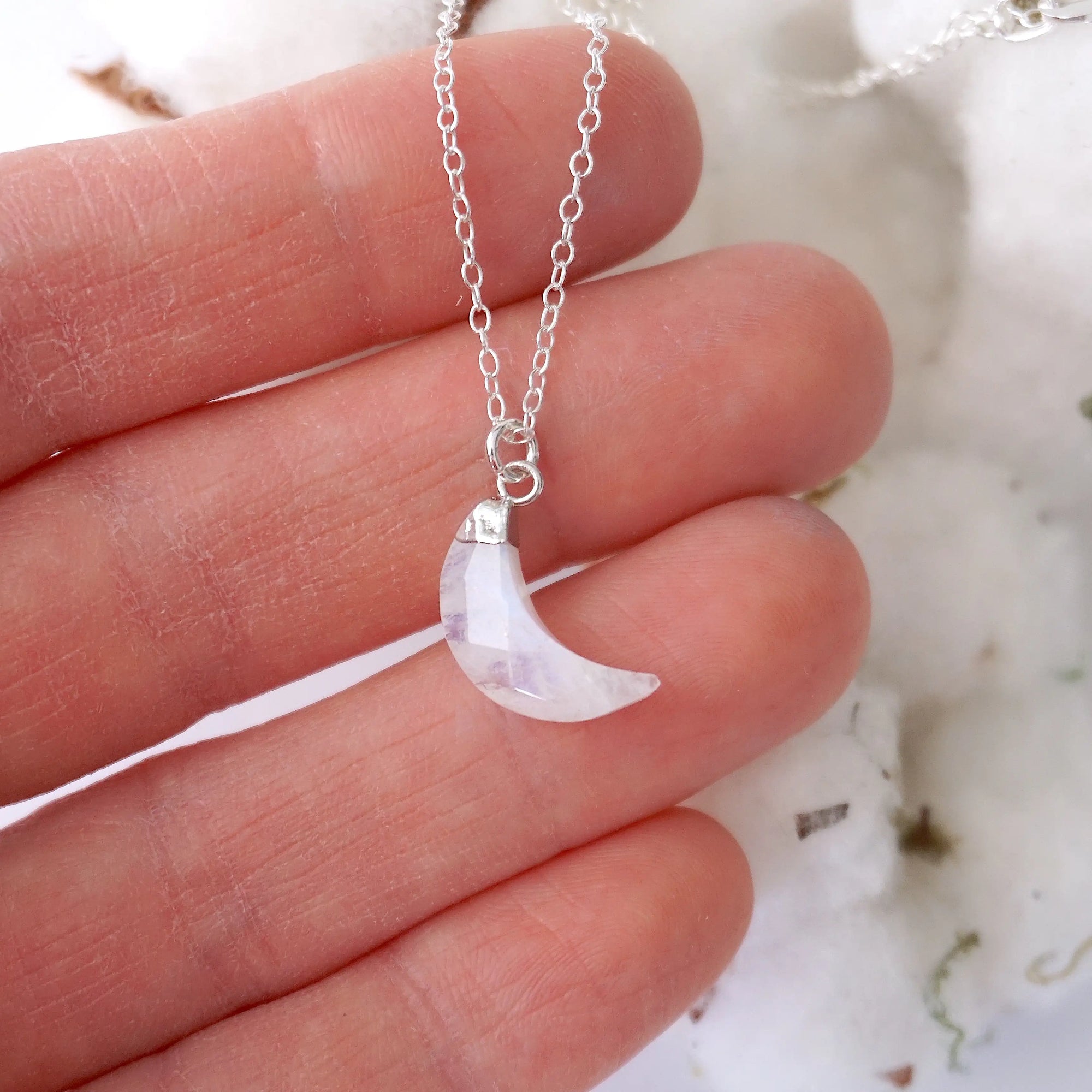 In-hand close-up of rainbow moonstone moon necklace for women, faceted crescent moon pendant in 925 sterling silver on 18 inch sterling silver chain (June birthstone).