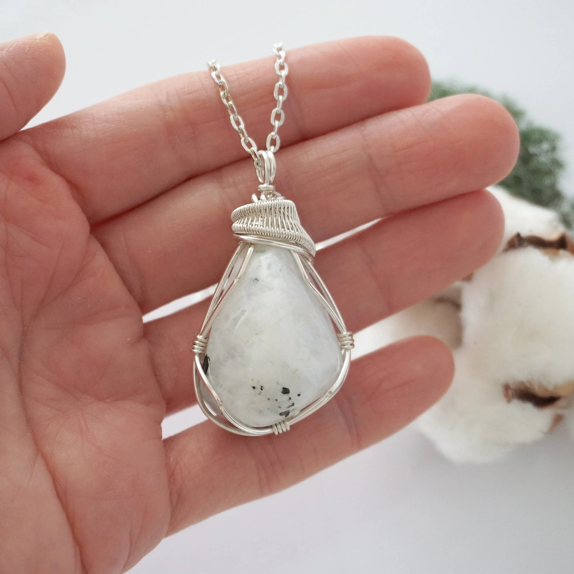 Rainbow moonstone necklace for women shown in hand for size reference with soft silver wire wrapped June birthstone pendant