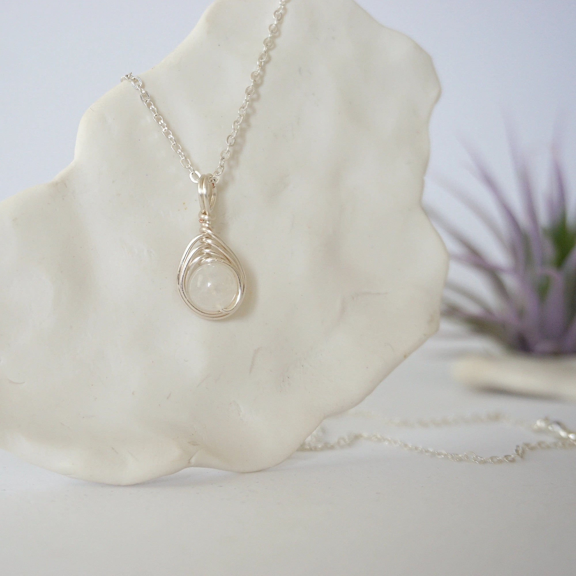 Right side angle close-up showing artisan soft silver wire wrapping around an 8mm rainbow moonstone bead on minimalist June birthstone necklace.