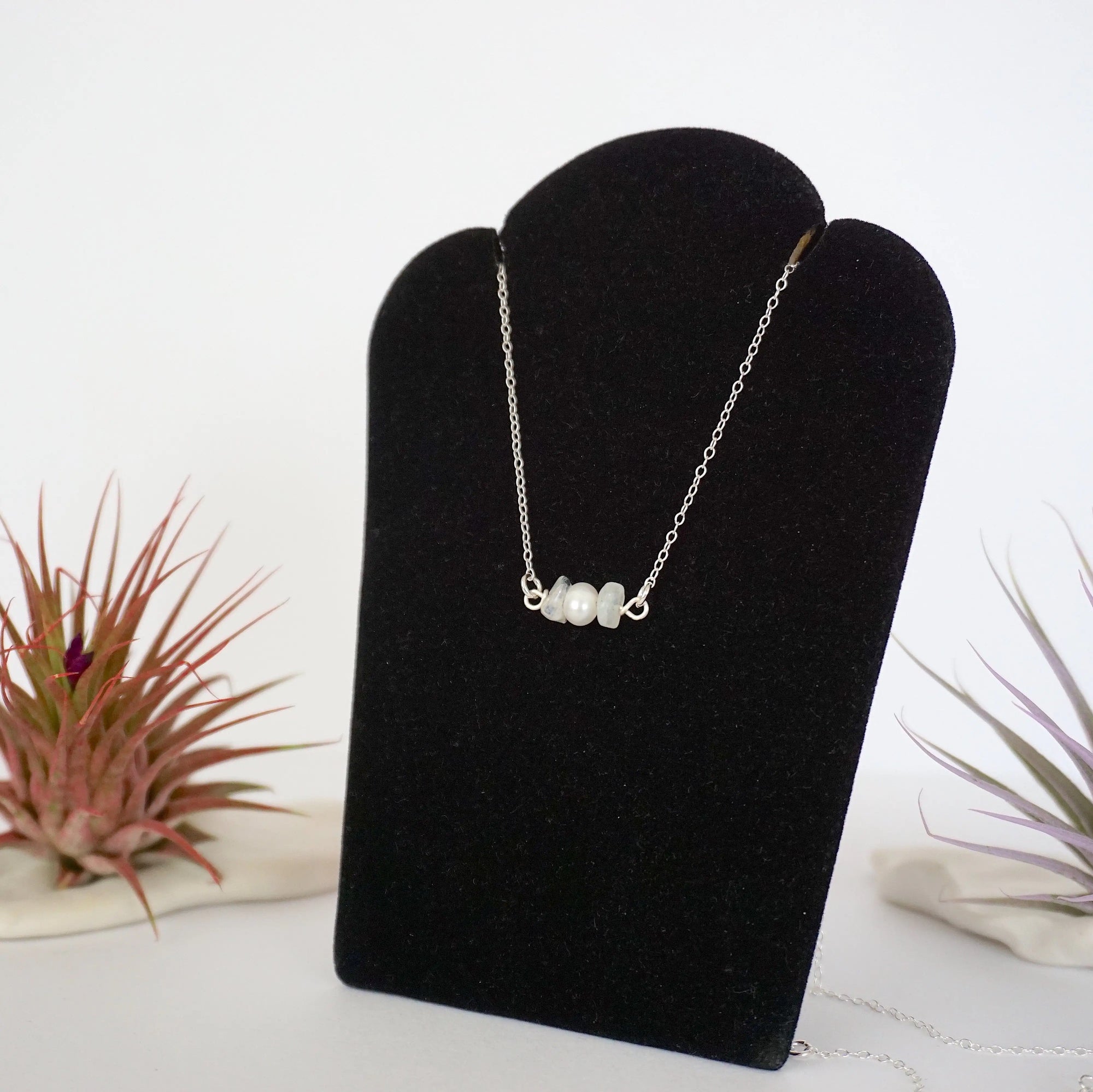 Left angle view of rainbow moonstone and pearl bar necklace in 925 sterling silver on jewelry display