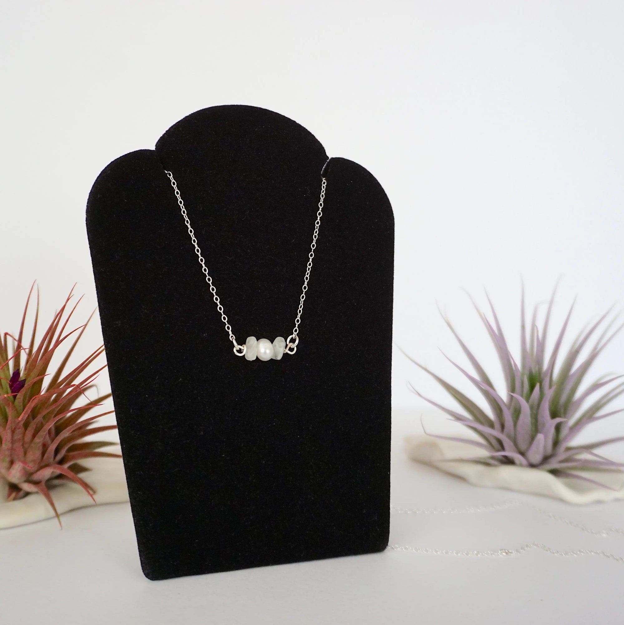 Right angle view of rainbow moonstone and freshwater pearl bar necklace in 925 sterling silver on jewelry display