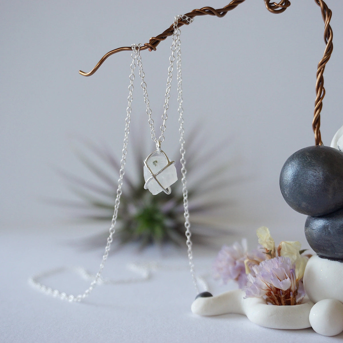 Back view of raw rainbow moonstone pendant showing sterling silver prong setting and bail on minimalist June birthstone necklace.
