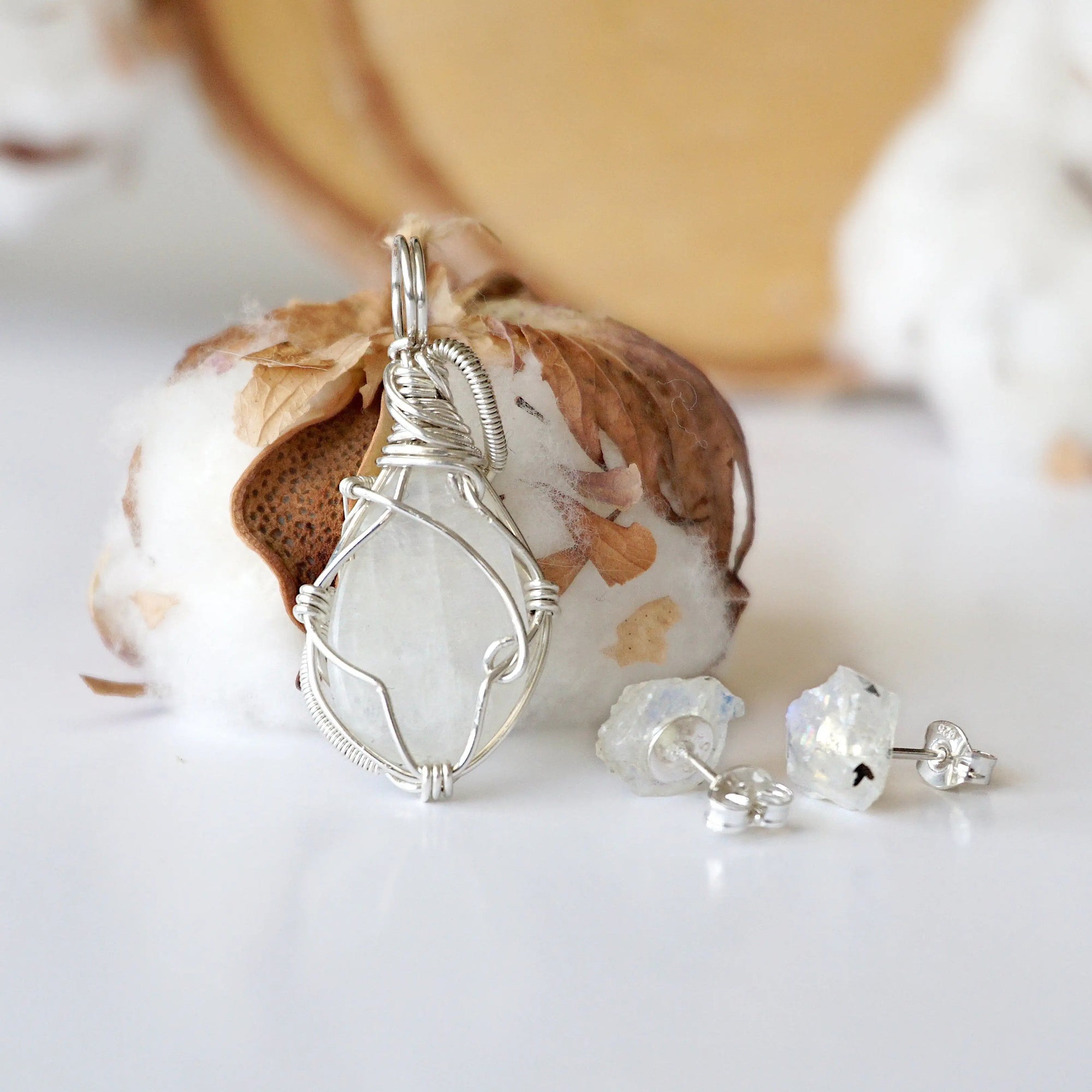 Back view of sterling silver wire wrapped rainbow moonstone cabochon pendant with matching raw moonstone stud earrings.