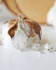 Back view of sterling silver wire wrapped rainbow moonstone cabochon pendant with matching raw moonstone stud earrings.