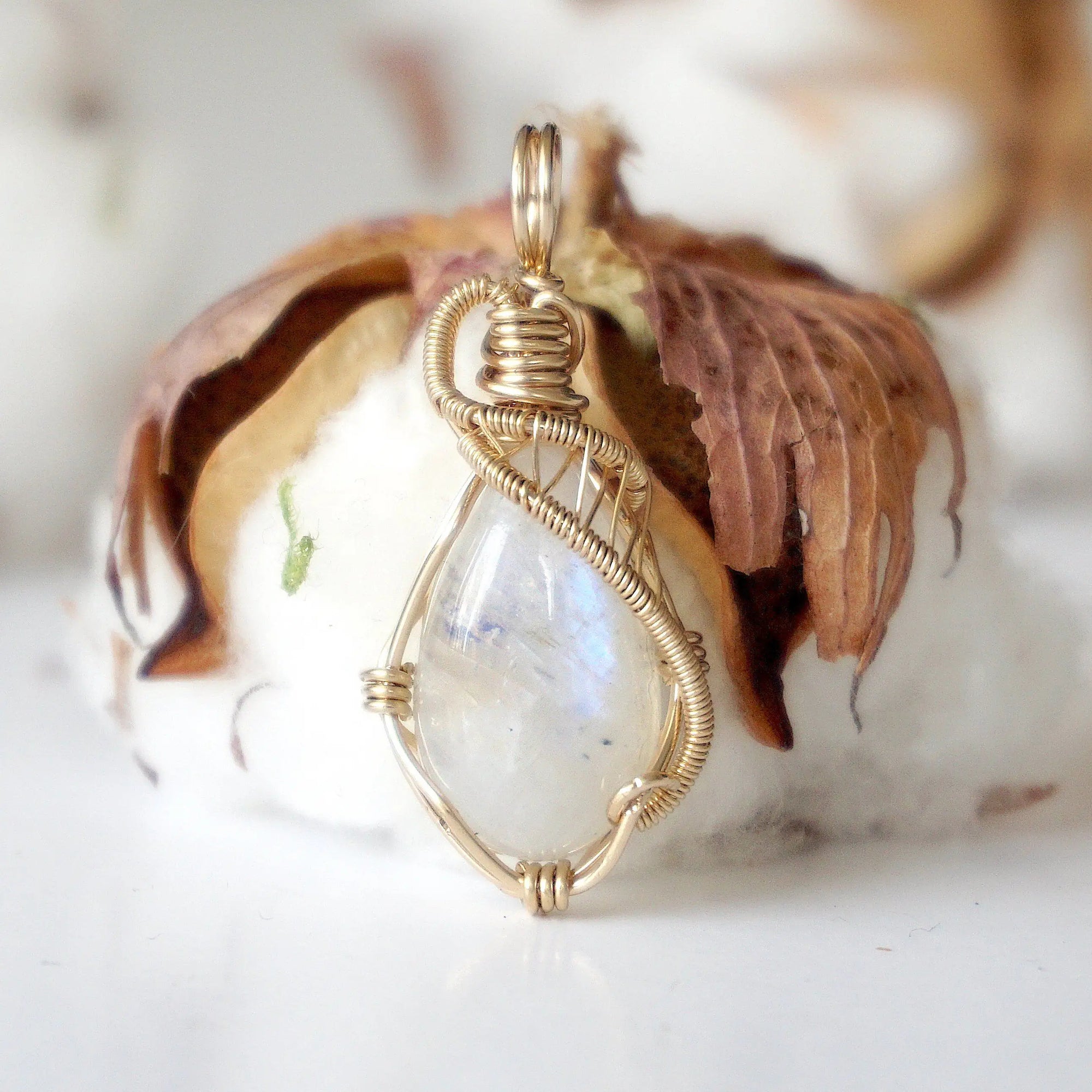 Front angle view of natural rainbow moonstone cabochon pendant with detailed 14k gold filled wire wrapping