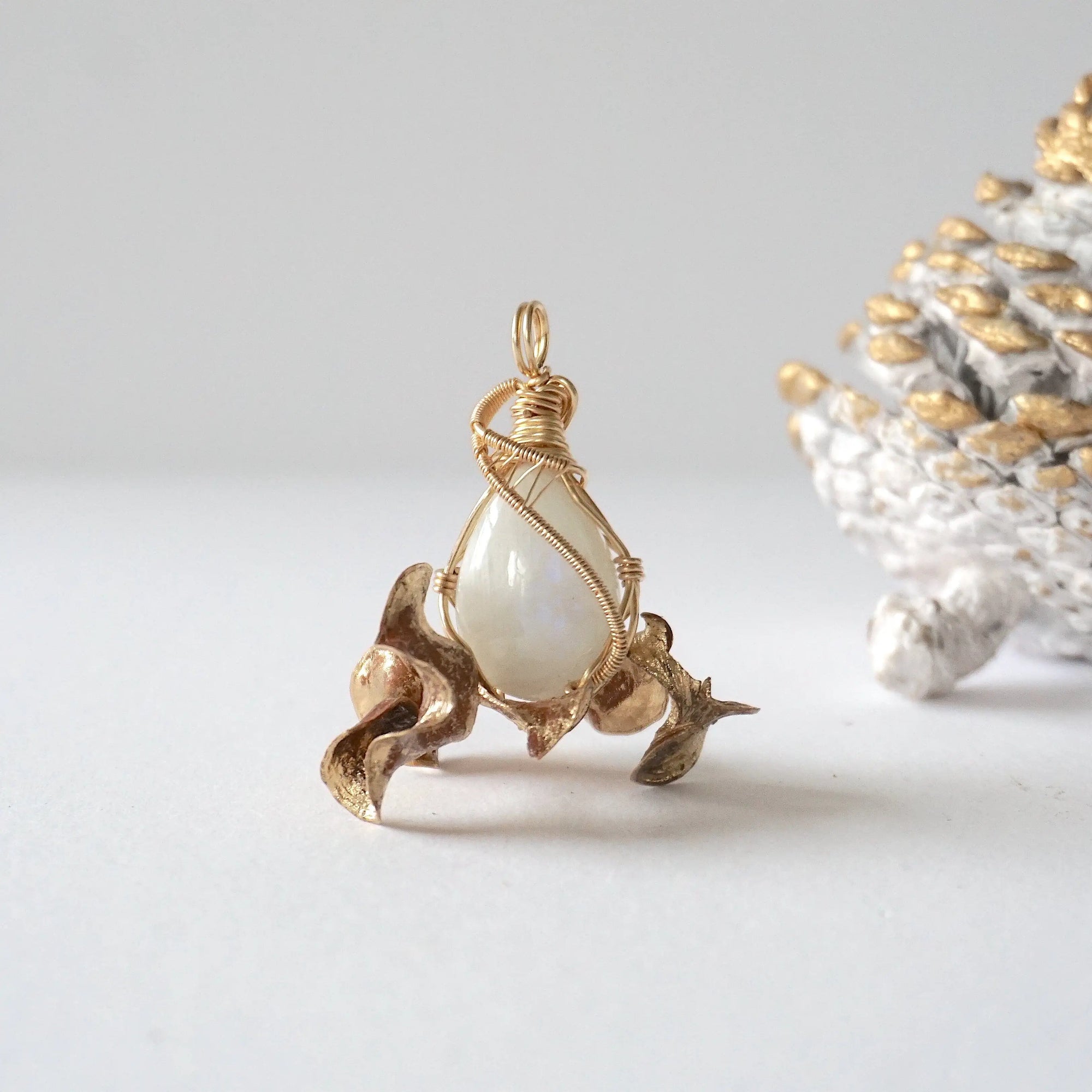 Front angle view of natural rainbow moonstone cabochon pendant with detailed 14k gold filled wire wrapping