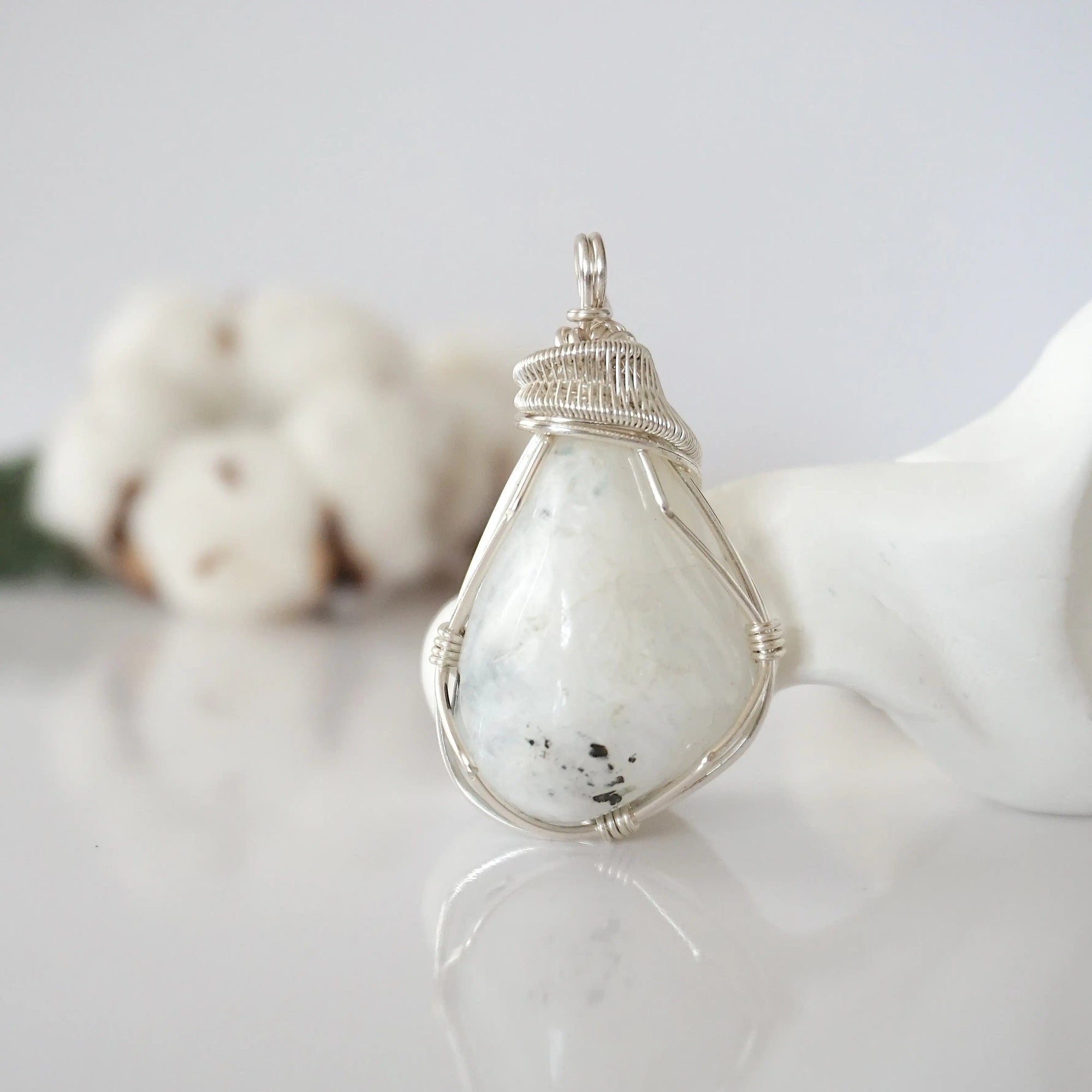 Front angle view of natural rainbow moonstone pendant with detailed artisan soft silver copper wire wrapping