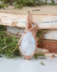 Front view of natural rainbow moonstone cabochon pendant highlighting soft luminous flash and rose gold filled wire wrap