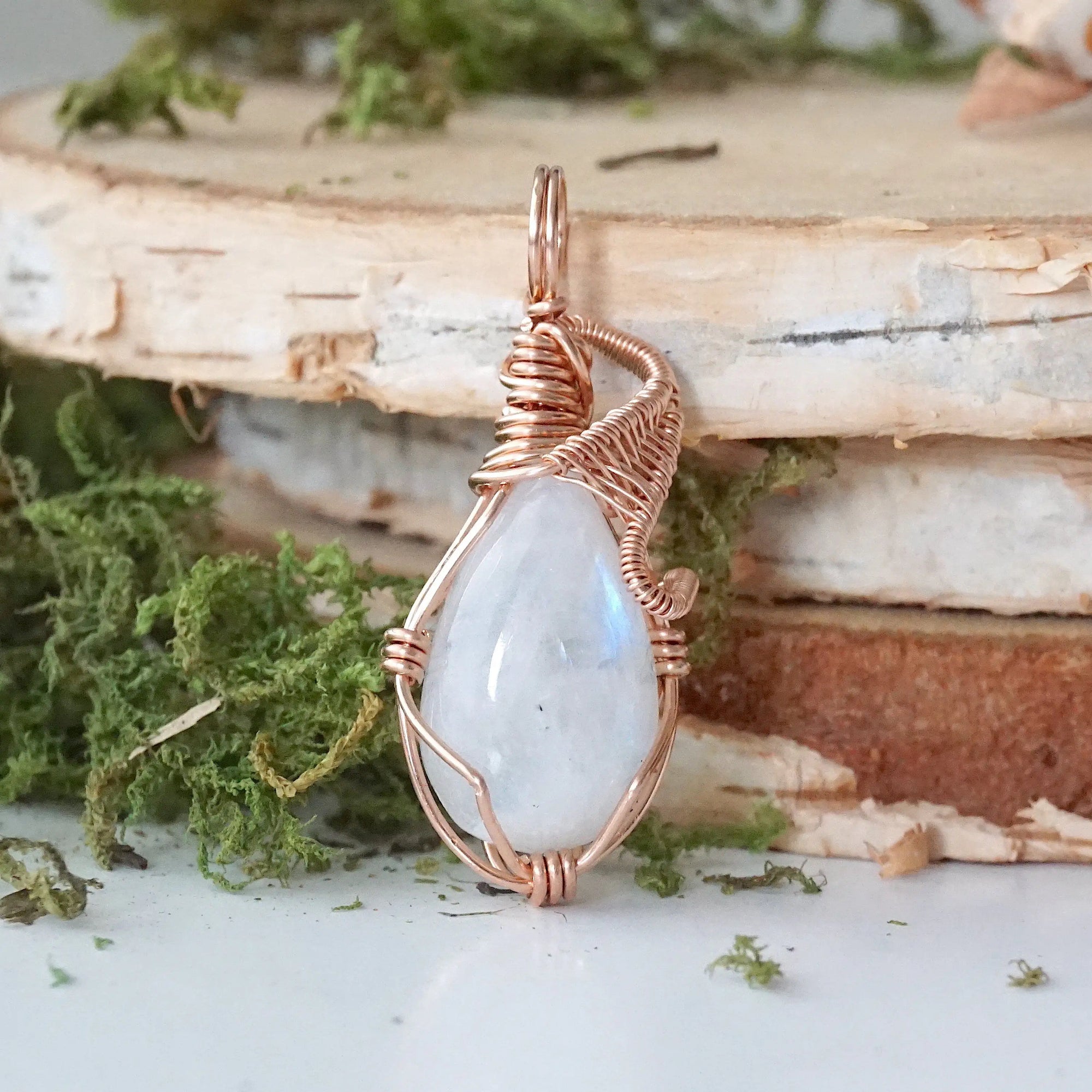 Front view of natural rainbow moonstone cabochon pendant highlighting soft luminous flash and rose gold filled wire wrap
