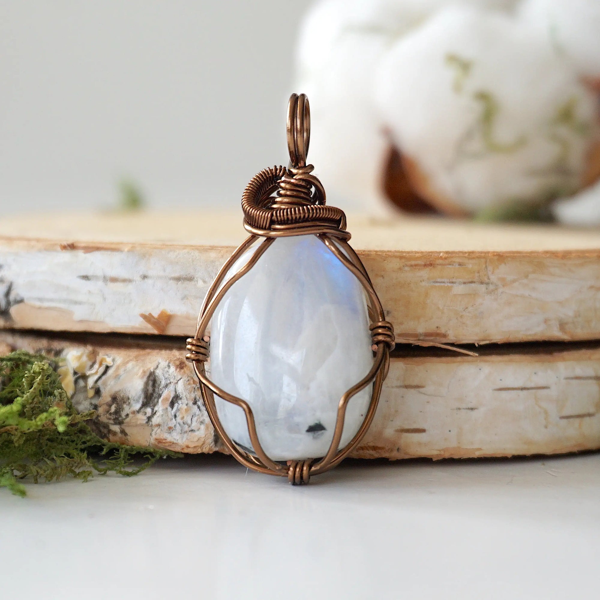 Front view of natural polished-raw rainbow moonstone pendant showing subtle flash and antique bronze copper wire wrapping