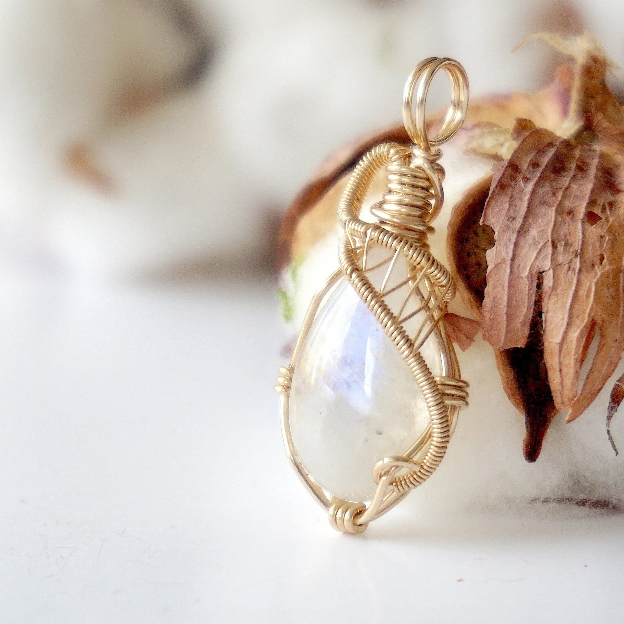 Left angle view of natural rainbow moonstone pendant highlighting artisan 14k gold filled wire wrapping