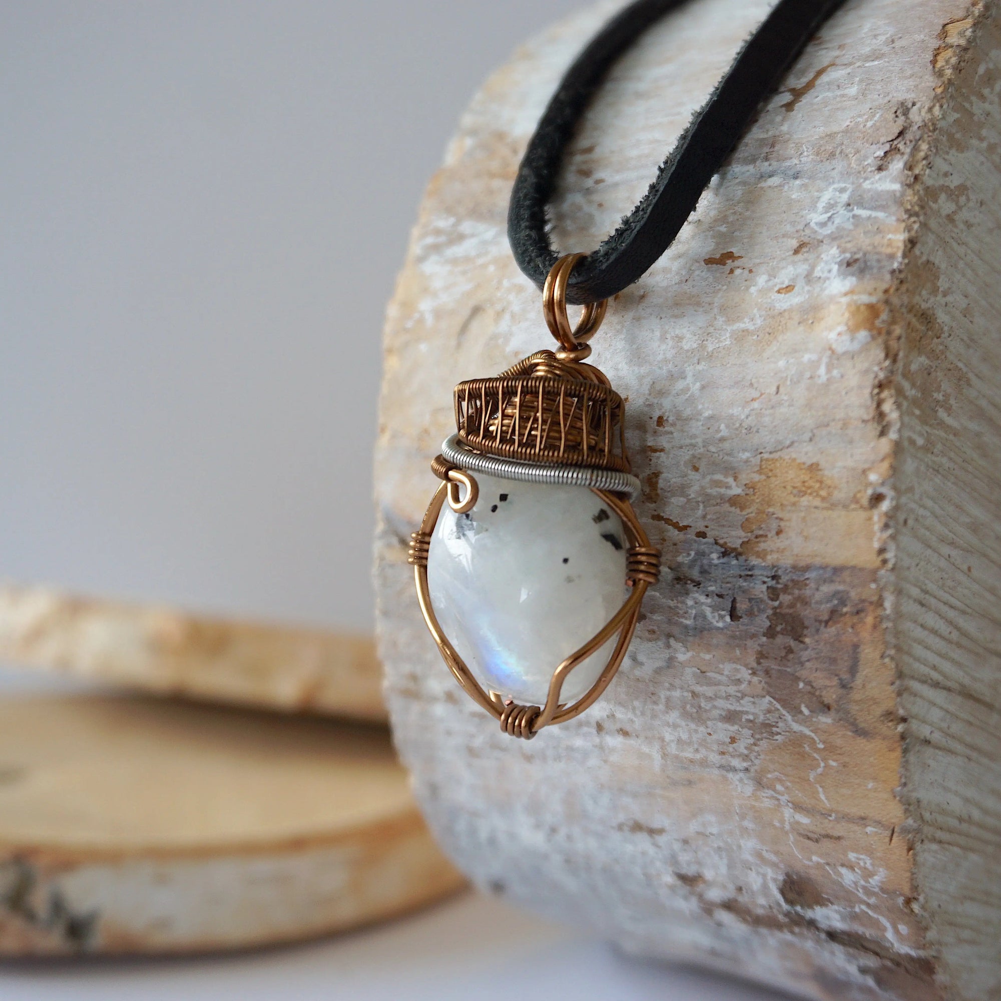 Left angle view of natural rainbow moonstone pendant highlighting artisan mixed metal wire wrapping