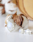 Left angle close-up of sterling silver wire wrapped rainbow moonstone cabochon pendant with matching raw moonstone stud earrings.