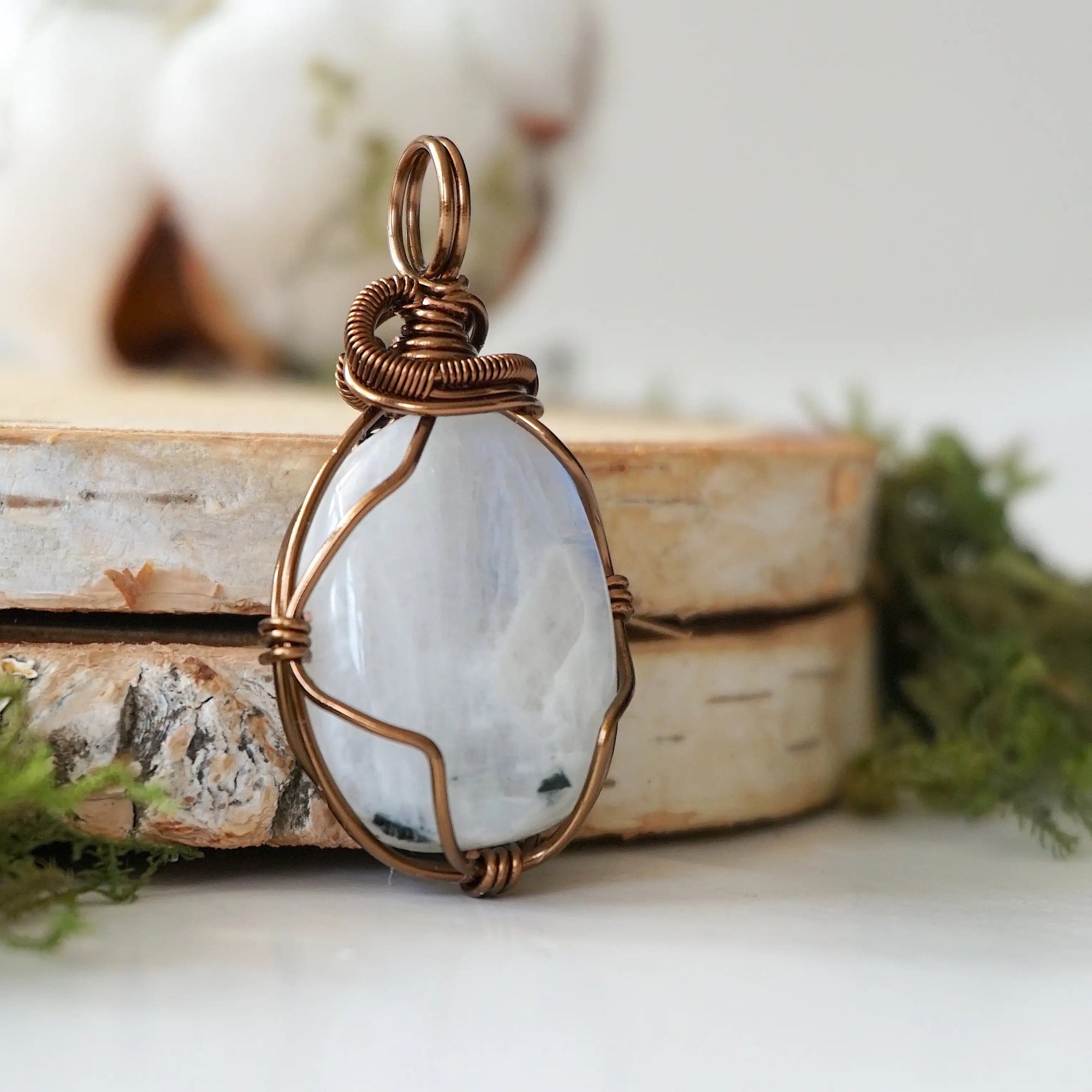 Right angle close-up of rainbow moonstone pendant highlighting detailed artisan antique bronze finish over copper wire wrapping
