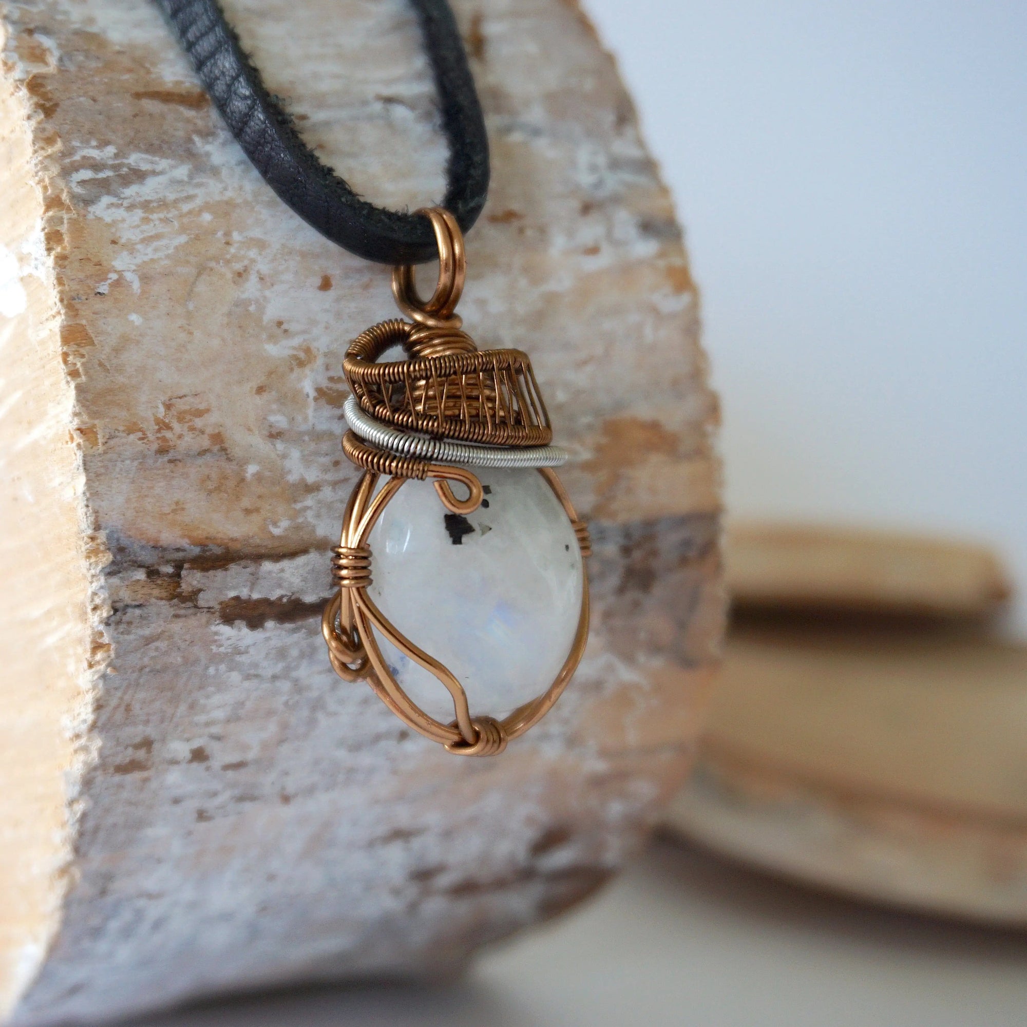 Right angle view of rainbow moonstone pendant showing handcrafted antique bronze and dark silver wire wrapping detail