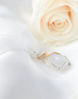 Right angle close-up of natural rainbow moonstone cabochon pendant with mixed sterling silver and 14k gold filled wire wrapping.