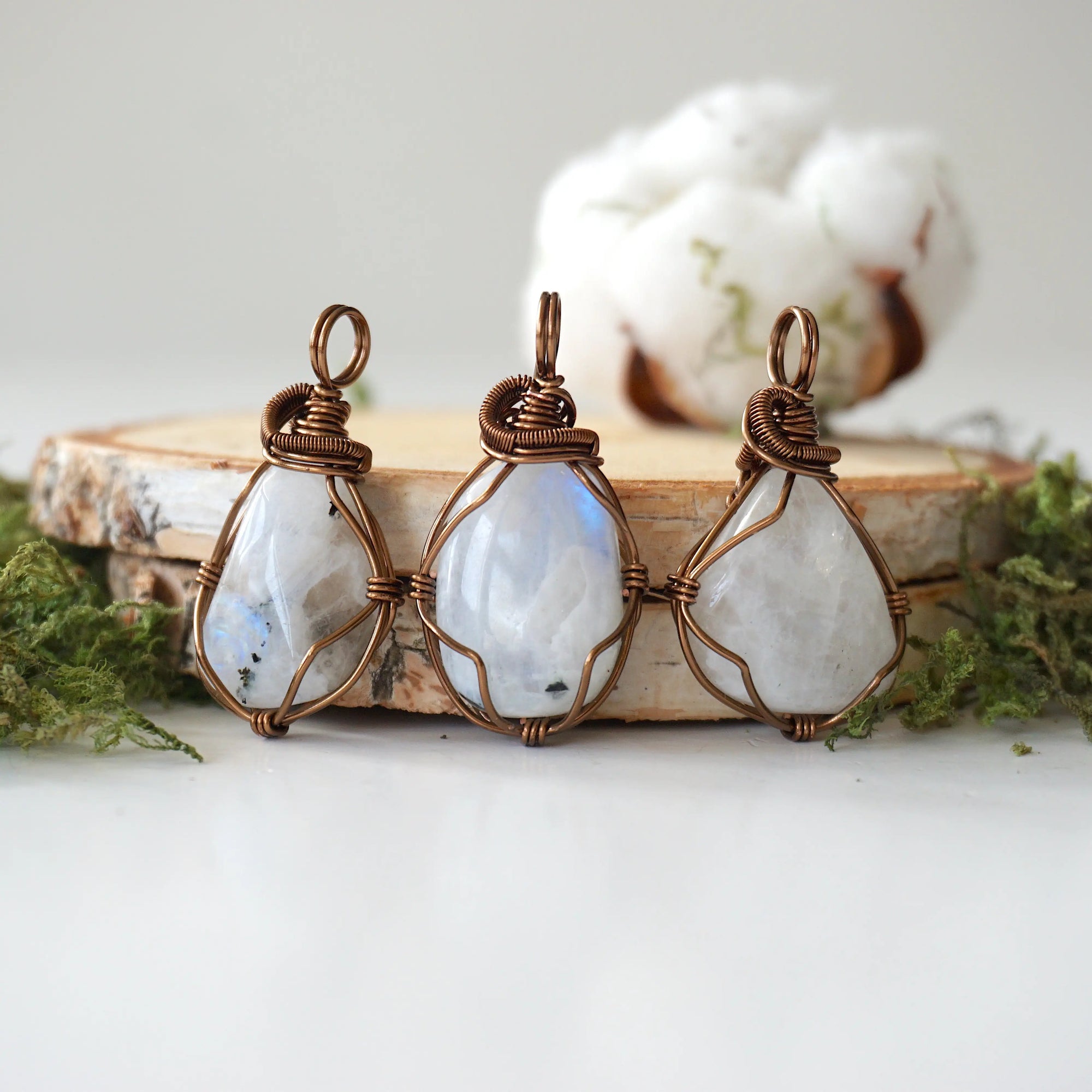 Three natural rainbow moonstone pendants showing variation in size, shape and colour shade in handmade wire wrapped jewelry