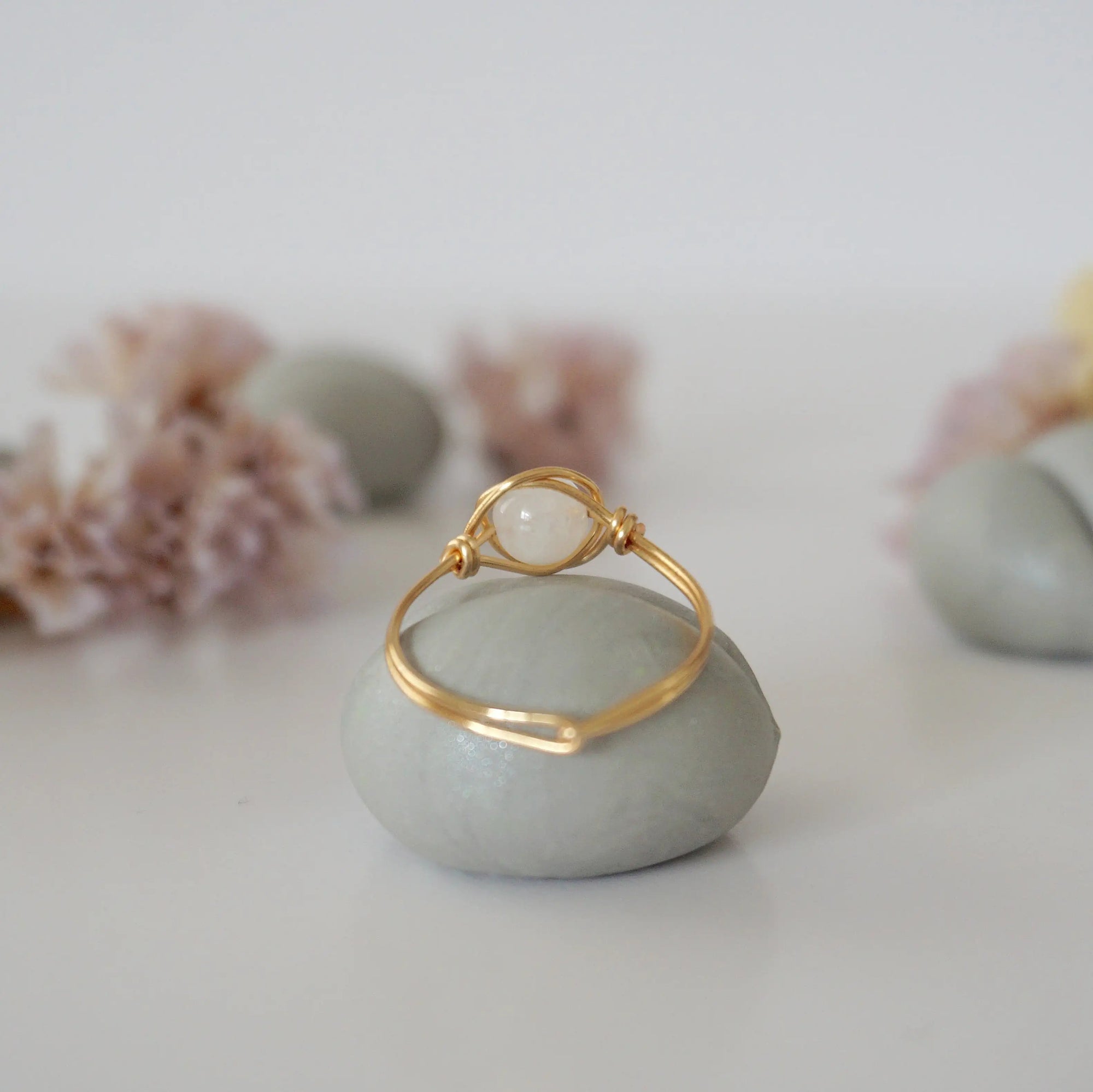 Back view of warm gold wire wrapped rainbow moonstone ring, minimalist band and handcrafted wrap detail.