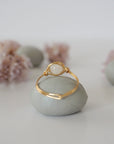 Back view of warm gold wire wrapped rainbow moonstone ring, minimalist band and handcrafted wrap detail.