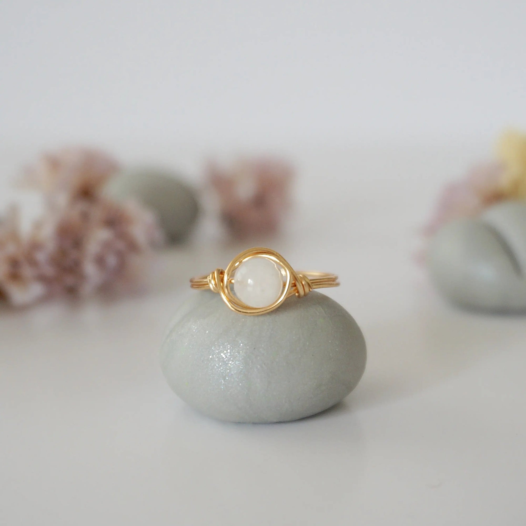 Front close-up of minimalist rainbow moonstone bead ring in warm gold wire wrap, June birthstone ring for women.