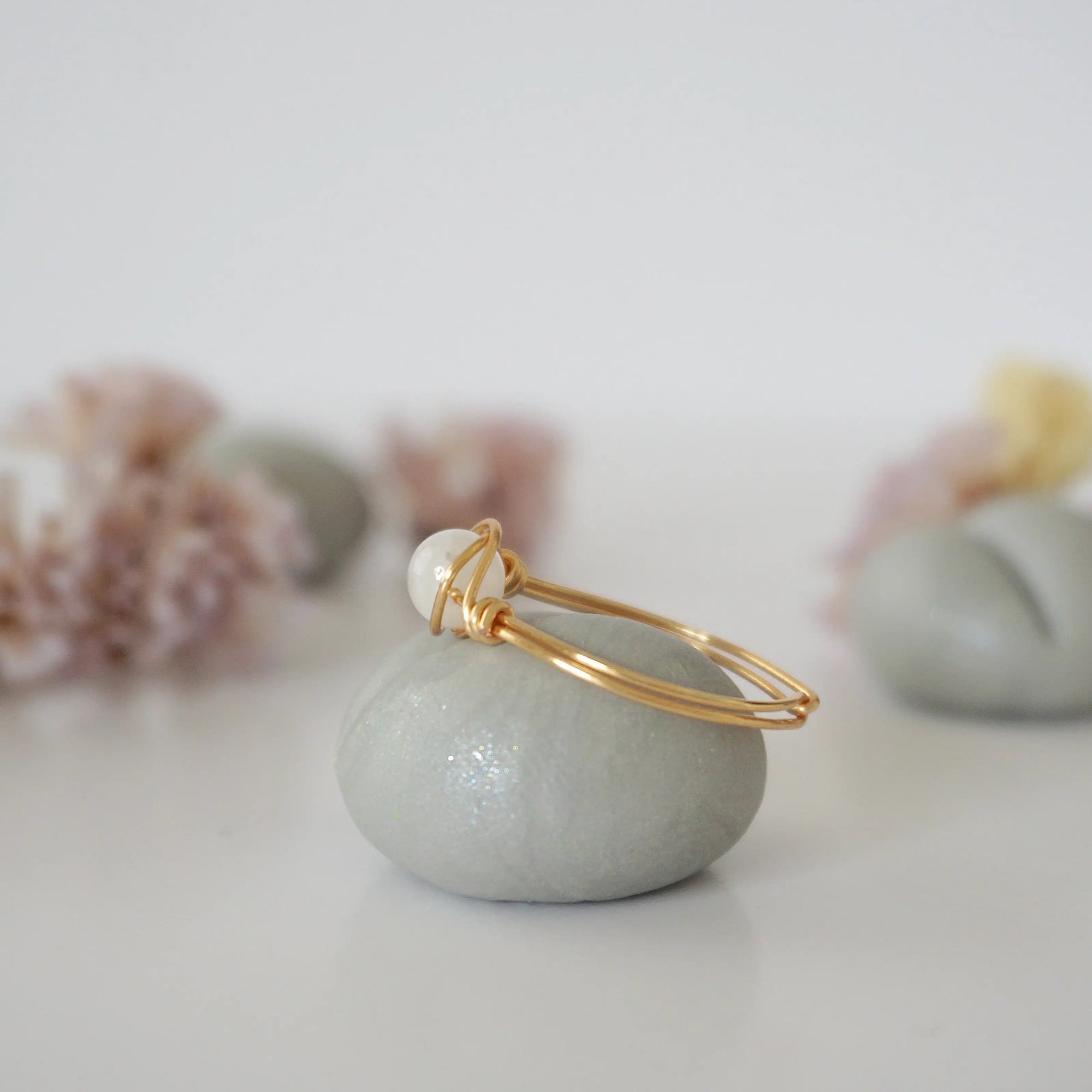 Side close-up of warm gold wire wrapped rainbow moonstone ring showing minimalist artisan wrapping detail.