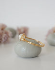 Side close-up of warm gold wire wrapped rainbow moonstone ring showing minimalist artisan wrapping detail.