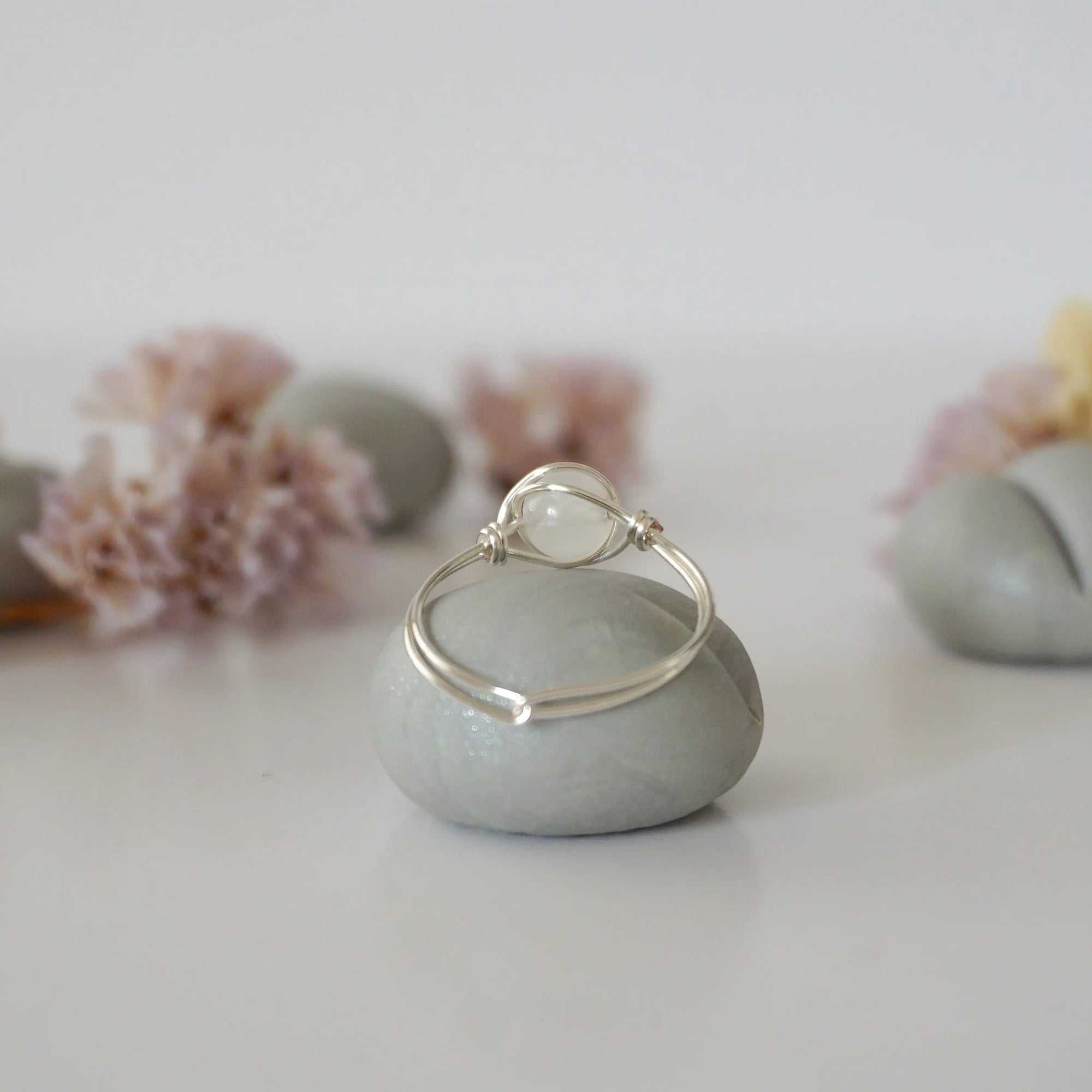 Back view of sterling silver wire wrapped rainbow moonstone ring, minimalist band and handcrafted wrap detail.