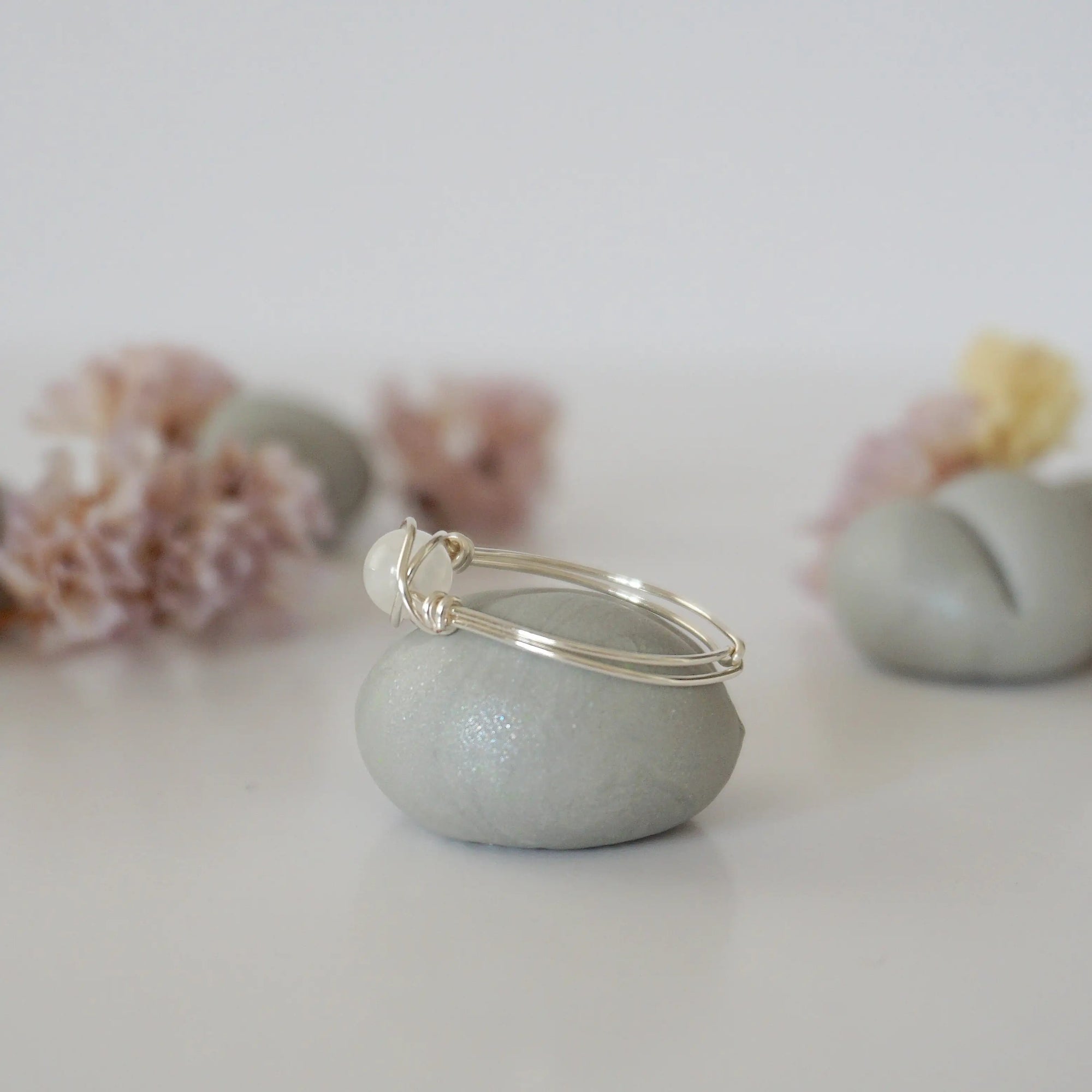 Side close-up of sterling silver wire wrapped rainbow moonstone ring showing minimalist artisan wrapping detail.