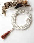 Top view of 108 bead rainbow moonstone mala necklace with rose quartz guru stone and earthy brown tassel, knotted silk cord design.