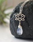 Left angle close-up highlighting handcrafted details of rainbow moonstone and lotus necklace, sterling silver lotus charm and faceted pear moonstone pendant.