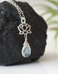 Right angle close-up showing artisan design of rainbow moonstone and lotus necklace, 925 sterling silver lotus charm with faceted pear rainbow moonstone drop.
