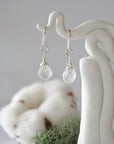 Detailed front view of handcrafted rainbow moonstone sterling silver drop earrings with natural faceted rainbow moonstone, artisan wire wrapping, hanging from a display – Designs by Nature Gems