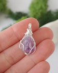 Simple raw amethyst pendant shown in hand for size reference