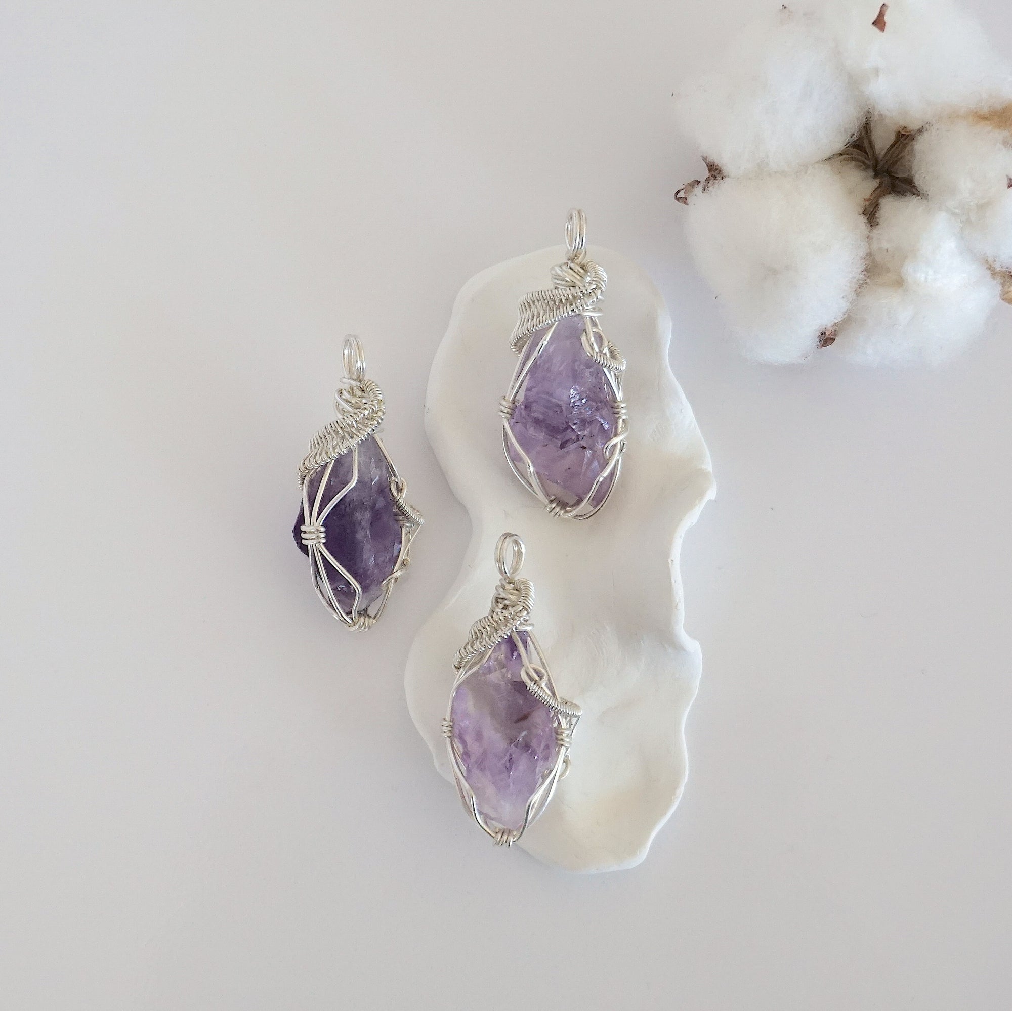 Three raw amethyst pendants showing natural variation in stone size, shape, and lavender colour — each one of a kind, February birthstone, 925 sterling silver wire wrapped, Designs by Nature Gems