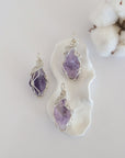 Three raw amethyst pendants showing natural variation in stone size, shape, and lavender colour — each one of a kind, February birthstone, 925 sterling silver wire wrapped, Designs by Nature Gems
