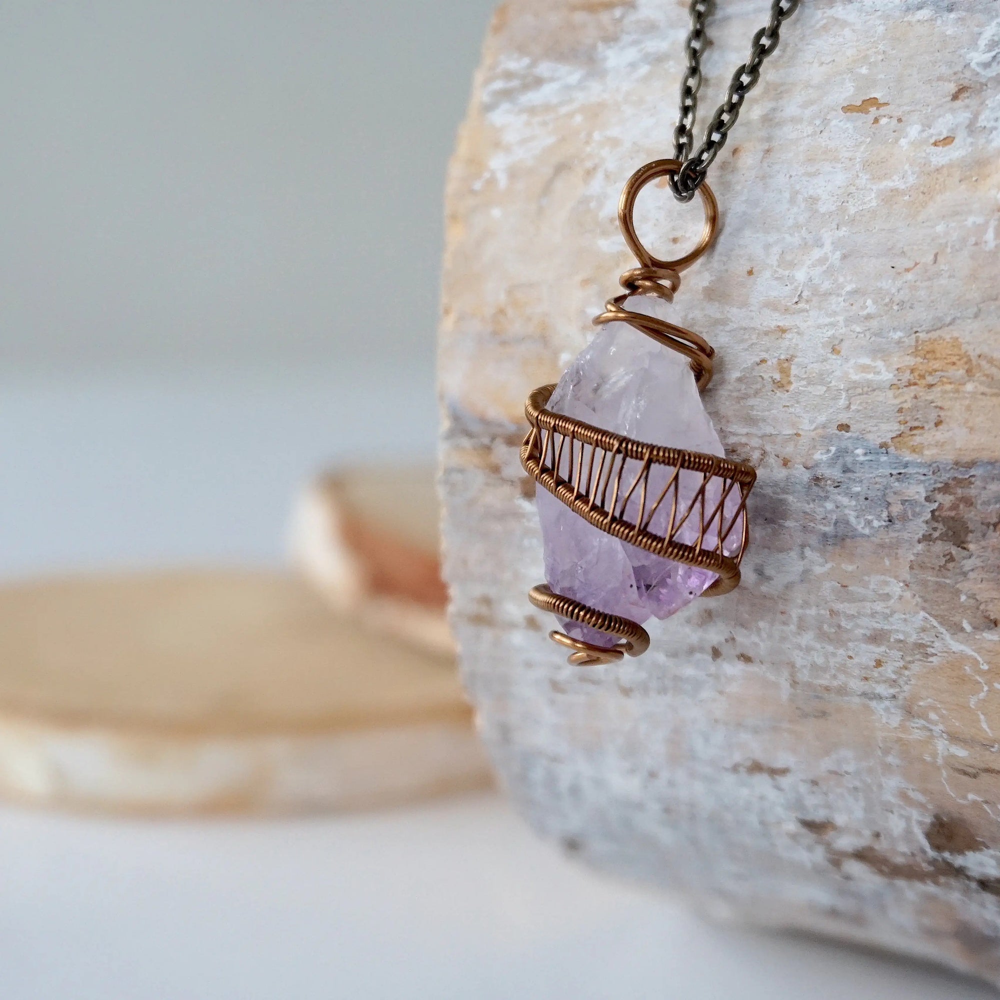 Left side detail of raw amethyst point pendant necklace with antique bronze copper wire wrap on antique bronze chain