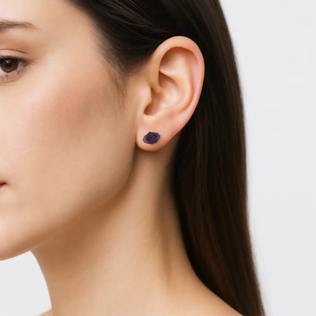 Raw amethyst stud earrings worn on female model's ear, natural unpolished amethyst stones, sterling silver posts