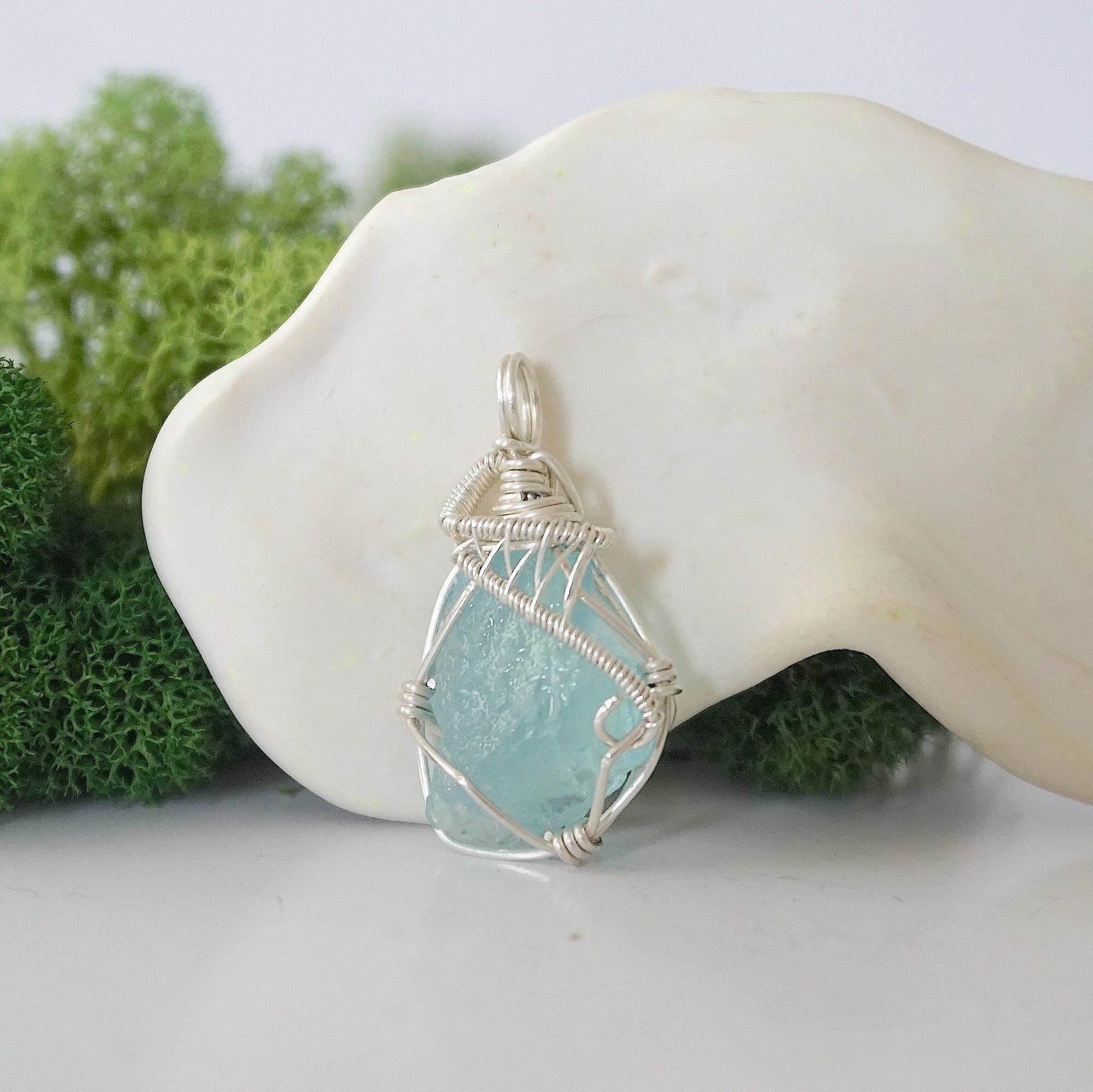 Front view of raw aquamarine pendant — natural unpolished pale blue aquamarine stone hand-wrapped in detailed 925 sterling silver wire, handcrafted artisan jewelry