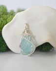 Front view of raw aquamarine pendant — natural unpolished pale blue aquamarine stone hand-wrapped in detailed 925 sterling silver wire, handcrafted artisan jewelry