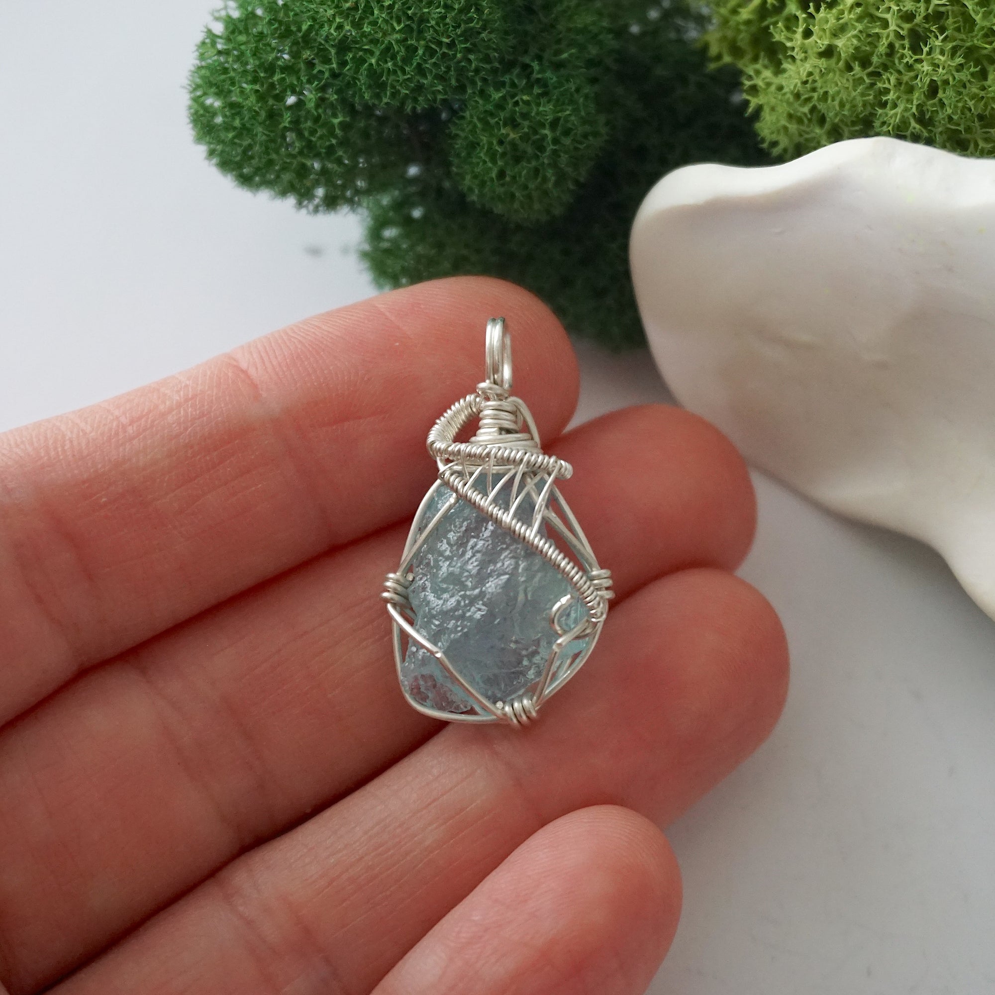 Handmade raw aquamarine pendant held in hand showing size — natural pale blue aquamarine stone wire wrapped in 925 sterling silver, 8-10 carats, one of a kind