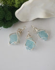 Three raw aquamarine pendants showing natural variation in stone size, shape, and pale blue tone — each one of a kind, March birthstone, 925 sterling silver wire wrapped, Designs by Nature Gems